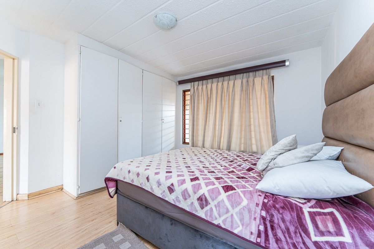 A bedroom featuring built-in cupboards, laminate flooring, and a ceiling light fixture.