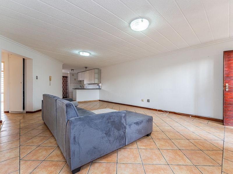 Open plan living area featuring tiled flooring, a functional kitchen corner with built-in cabinetry, and direct access to the main entrance.
