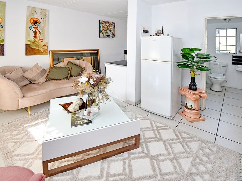 Open plan living area featuring tiled flooring, leading directly into a functional bathroom with a pedestal sink and toilet.