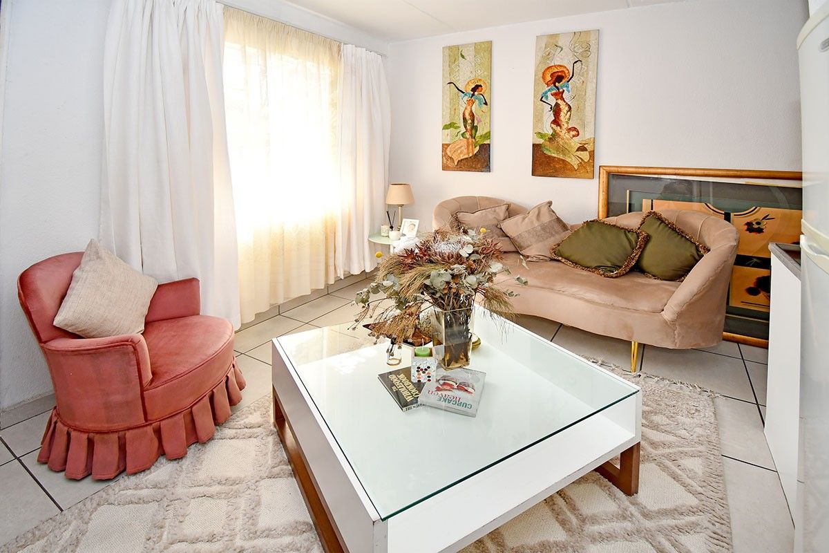 A bright living room featuring tiled flooring and large windows with curtains, providing a comfortable and well-lit space.