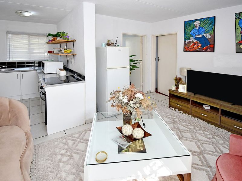 Open-plan living area featuring a functional kitchen with built-in cabinetry, tiled flooring, and a seamless flow into the adjacent living space.