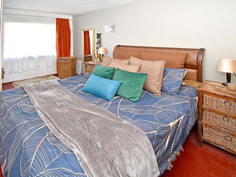A bedroom featuring a large window and painted concrete flooring, offering a functional space ready for cosmetic updates.