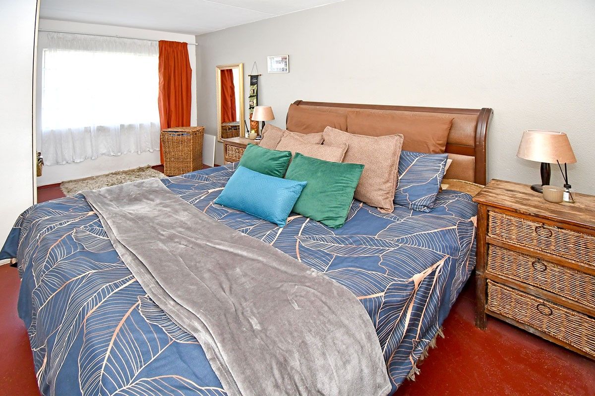 A bedroom featuring a large window and painted concrete flooring, offering a functional space ready for cosmetic updates.