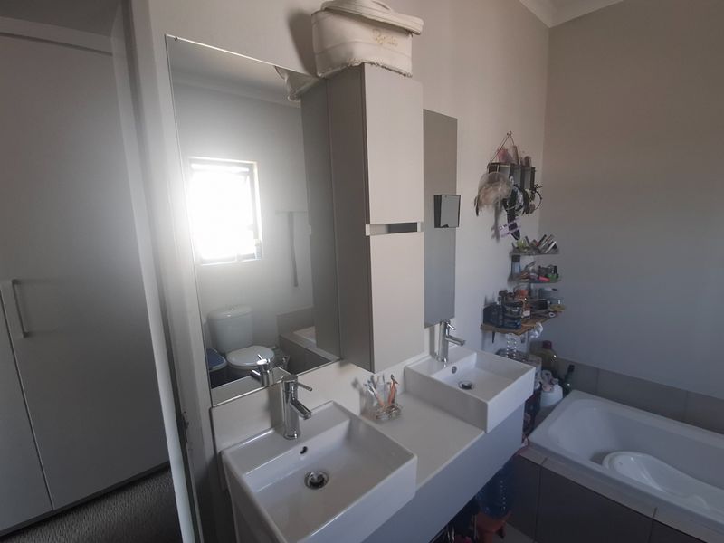 A modern bathroom featuring a double vanity with integrated storage, a bathtub, and a toilet, finished with contemporary fixtures.