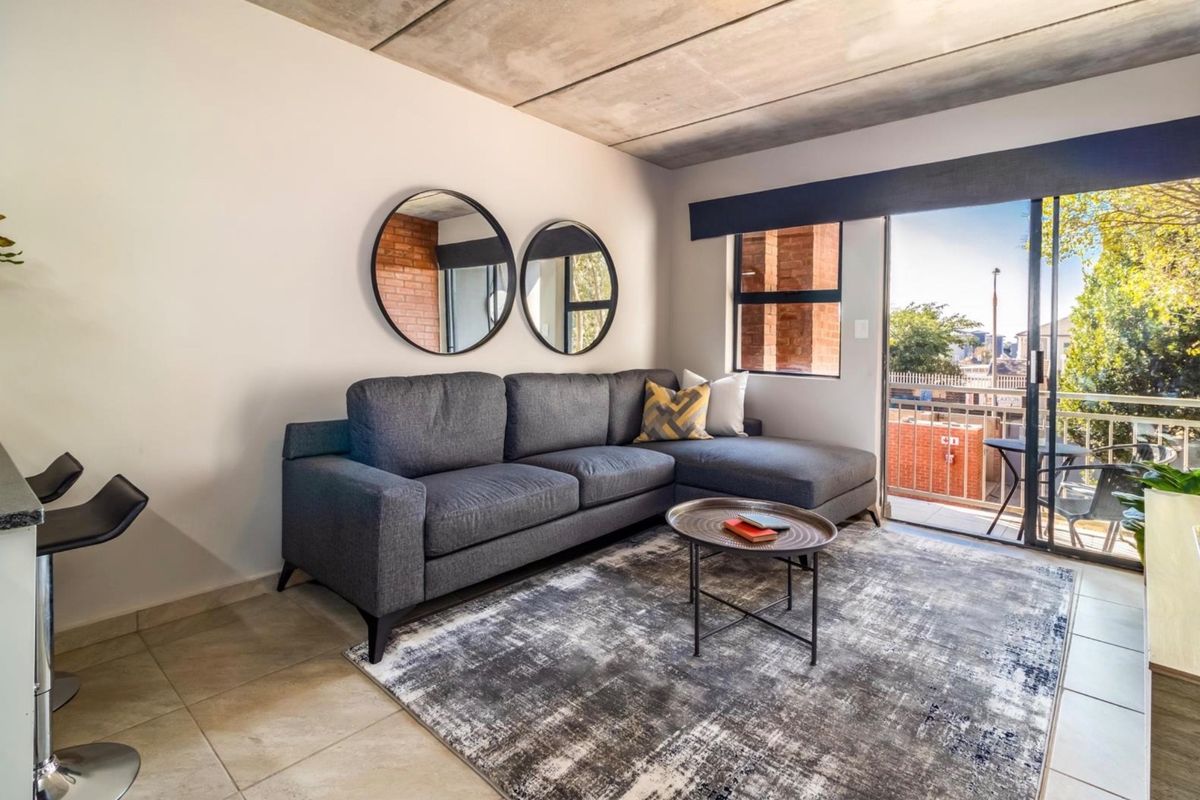Modern living room featuring an exposed concrete ceiling, tiled flooring, and a sliding glass door providing access to a private balcony.