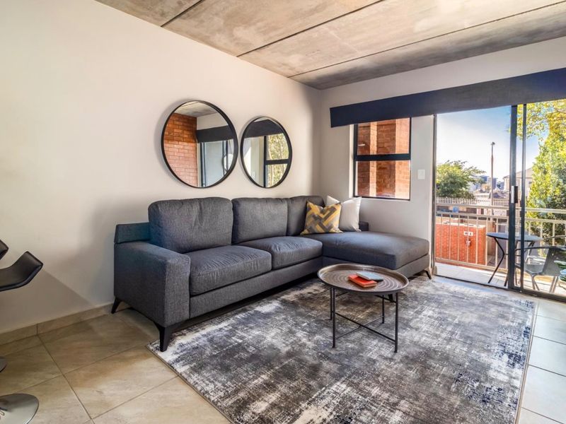 Modern living room featuring an exposed concrete ceiling, tiled flooring, and a sliding glass door providing access to a private balcony.