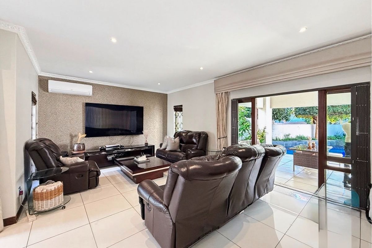 Spacious living room featuring tiled flooring, a textured feature wall, split-system air conditioning, and large sliding glass doors opening to the patio.