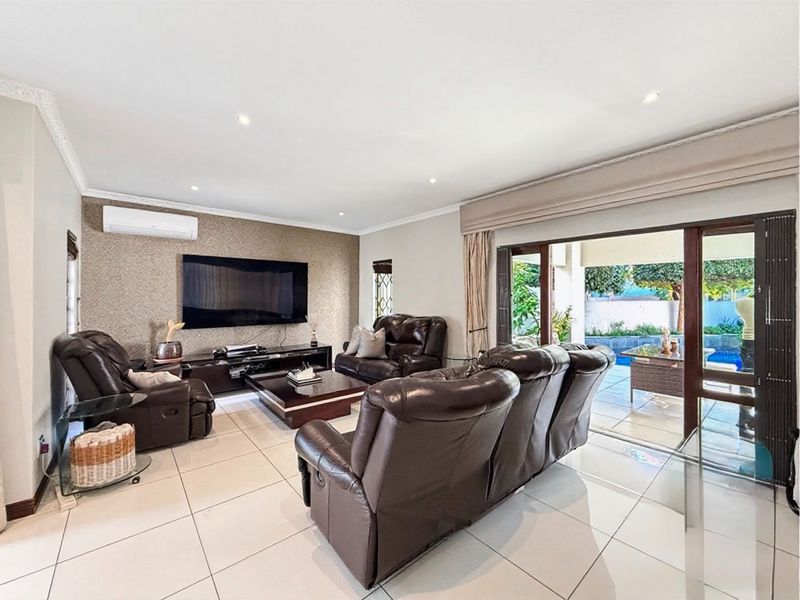Spacious living room featuring tiled flooring, a textured feature wall, split-system air conditioning, and large sliding glass doors opening to the patio.