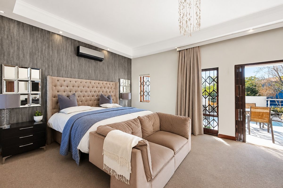 Spacious bedroom featuring a feature wall, air conditioning, and direct access to an outdoor patio area through a sliding glass door.