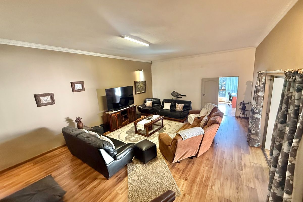 Spacious living room featuring laminate flooring and coved ceilings, providing a comfortable and functional area for relaxation and family gatherings.