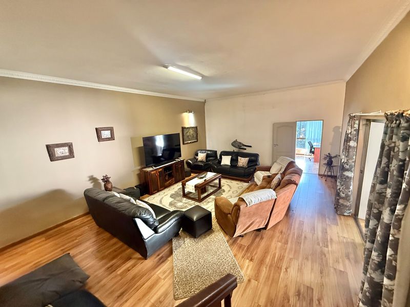 Spacious living room featuring laminate flooring and coved ceilings, providing a comfortable and functional area for relaxation and family gatherings.