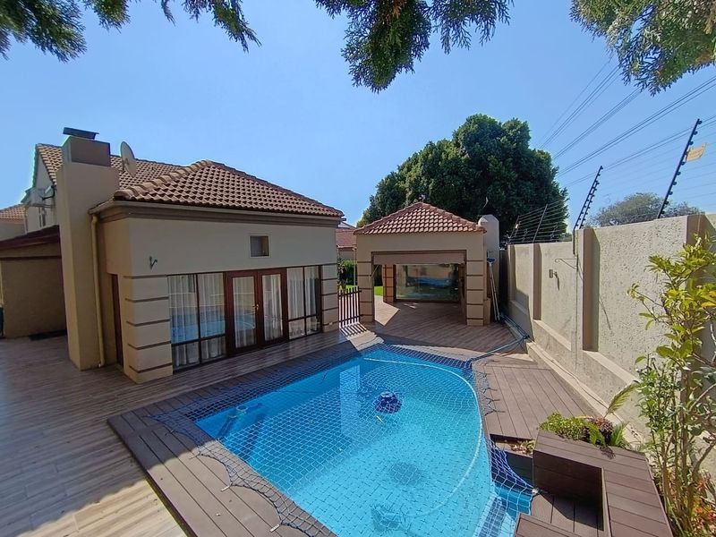 A well-maintained outdoor pool area featuring a swimming pool with decking, a covered gazebo, and secure perimeter walling with electric fencing.