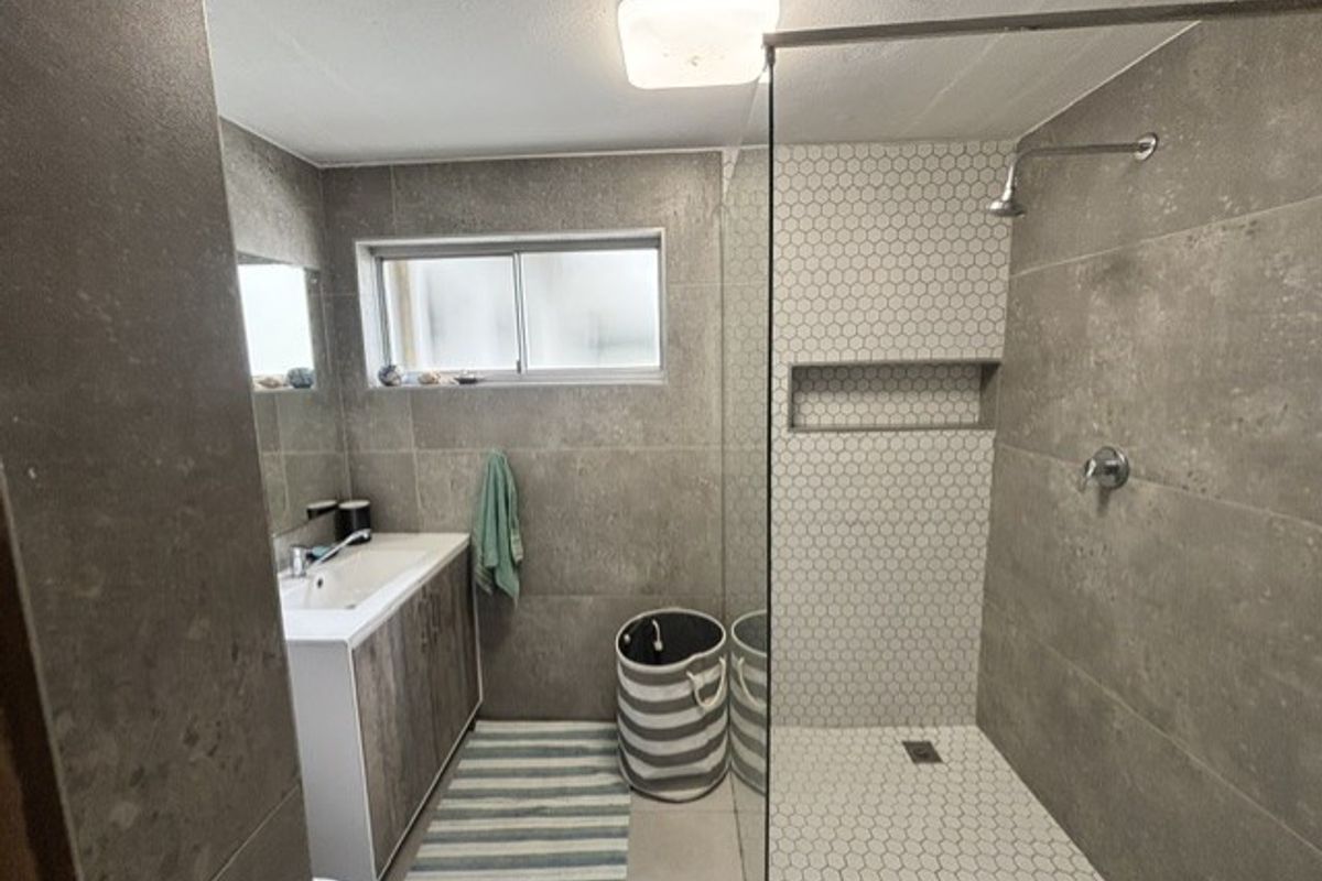 Modern bathroom featuring a walk-in shower with a glass screen, built-in niche, and a vanity unit with a basin.