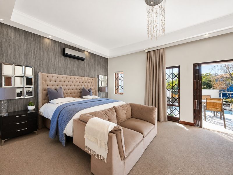 Spacious bedroom featuring a feature wall, air conditioning, and direct access to an outdoor patio area through a sliding glass door.