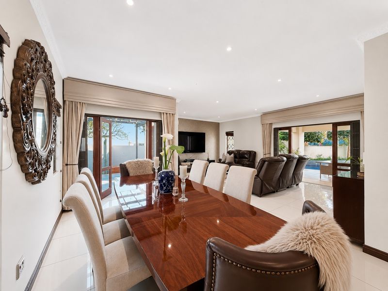 Spacious open-plan dining and living area featuring polished tiled floors, recessed lighting, and seamless access to the outdoor patio and pool area.