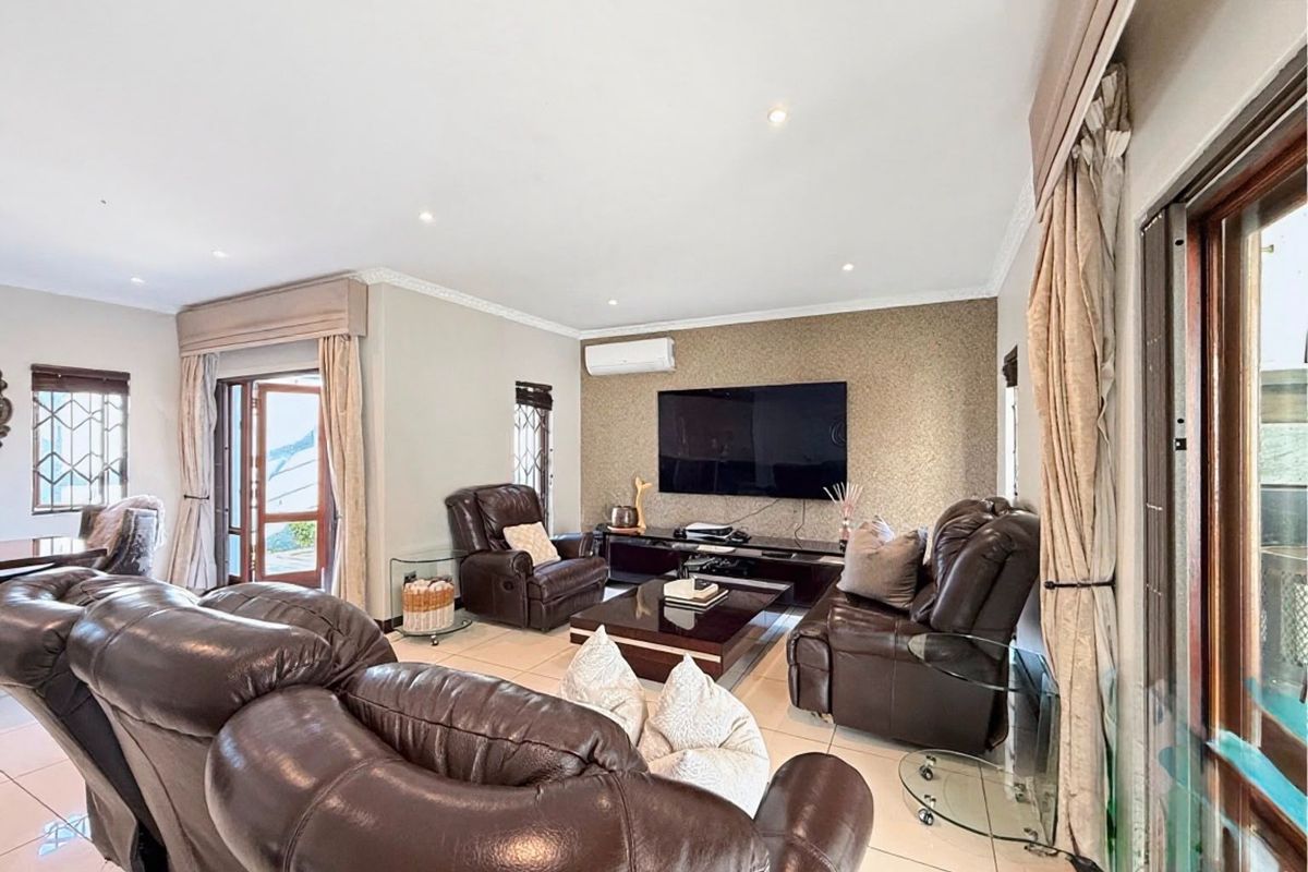 Spacious living room featuring tiled flooring, recessed downlighting, a textured feature wall, and direct access to outdoor areas through sliding glass doors.