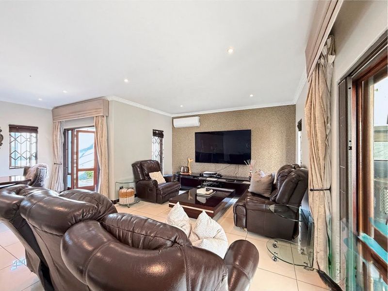 Spacious living room featuring tiled flooring, recessed downlighting, a textured feature wall, and direct access to outdoor areas through sliding glass doors.