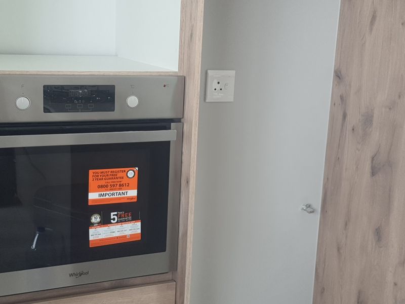 A modern kitchen featuring a built-in stainless steel oven set within wood-look cabinetry.