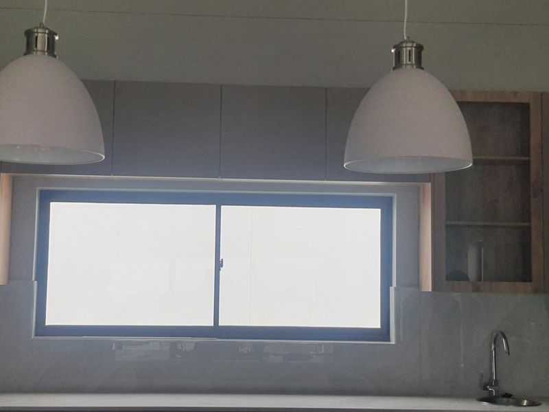 A modern kitchen area featuring sleek cabinetry, a tiled backsplash, a functional sink, and contemporary pendant lighting above the workspace.