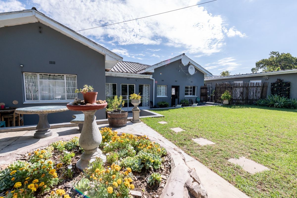 A spacious rear garden featuring a concrete patio, a raised garden bed, and a well-maintained lawn area adjacent to the house.