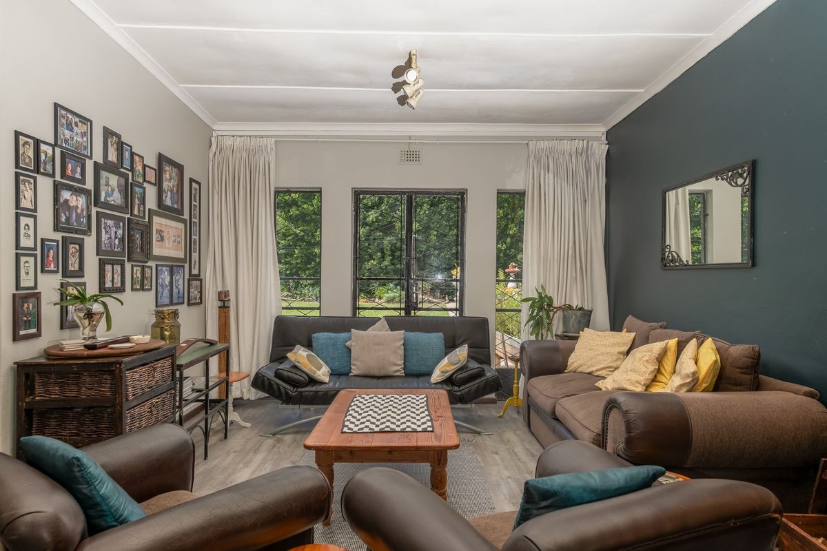 A comfortable living room featuring laminate flooring, a dark accent wall, and large french doors that provide natural light and garden views.