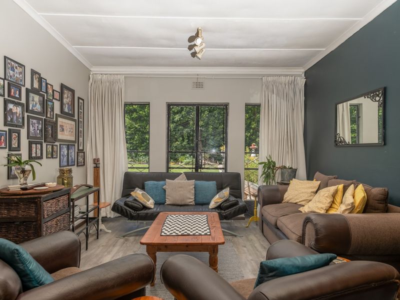 A comfortable living room featuring laminate flooring, a dark accent wall, and large french doors that provide natural light and garden views.
