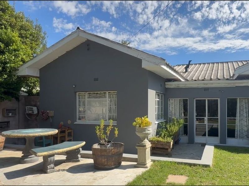 Rear view of the house featuring a concrete patio area, steel-framed windows and doors, and a tiled roof with visible exterior wall finishes.