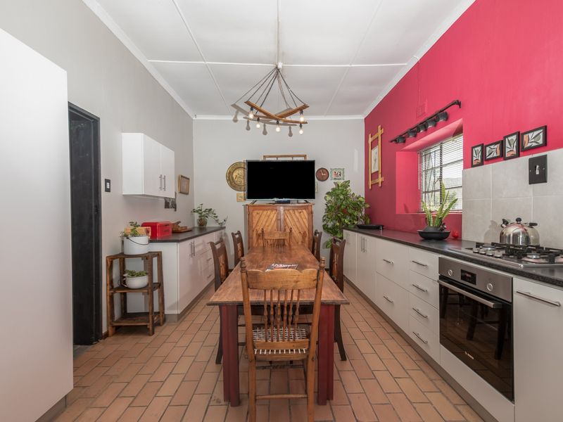 Open-plan kitchen and dining area featuring tiled flooring, built-in cabinetry, gas hob, and electric oven with a vibrant accent wall.