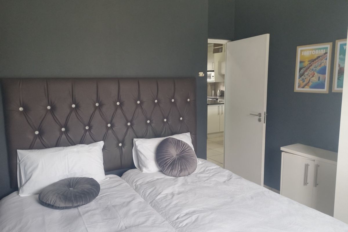 A well-maintained bedroom featuring dark accent walls and a view through to the kitchen area.