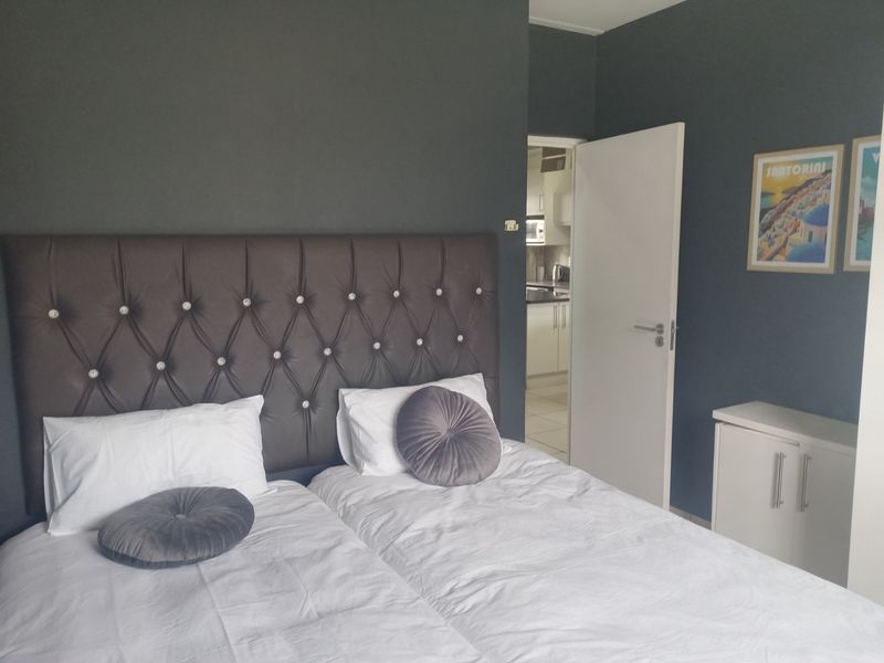 A well-maintained bedroom featuring dark accent walls and a view through to the kitchen area.