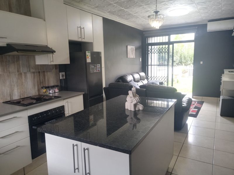 Open-plan living area featuring a modern kitchen with a granite-topped island, built-in appliances, and direct access to the outdoor space through sliding glass doors.