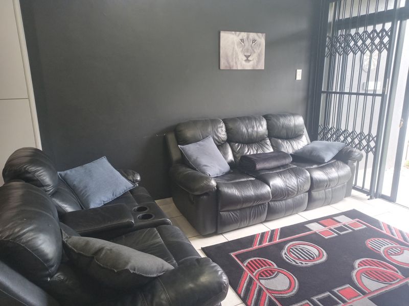 A living room area featuring dark painted walls, tiled flooring, and a security gate leading to the exterior.