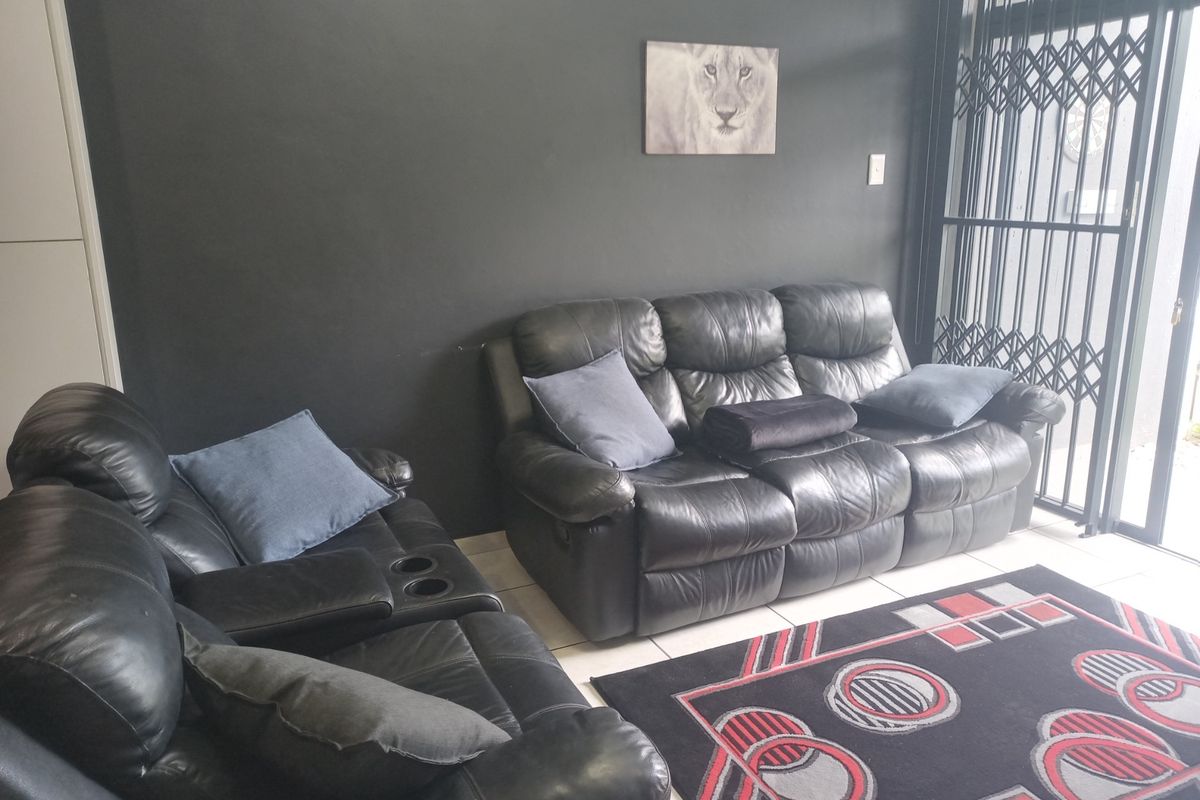A living room area featuring dark painted walls, tiled flooring, and a security gate leading to the exterior.