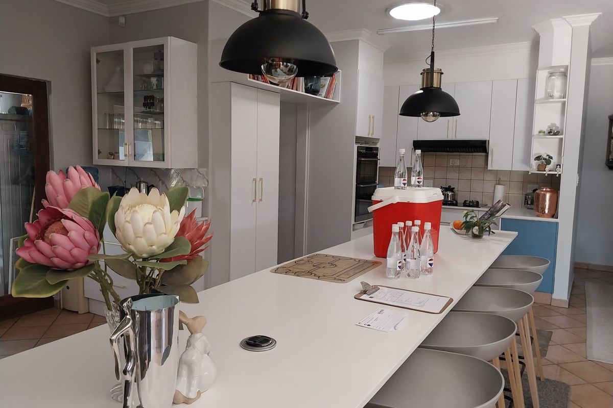 Modern kitchen featuring a large central island with breakfast bar seating, built-in oven, extractor fan, and ample white cabinetry with glass display units.