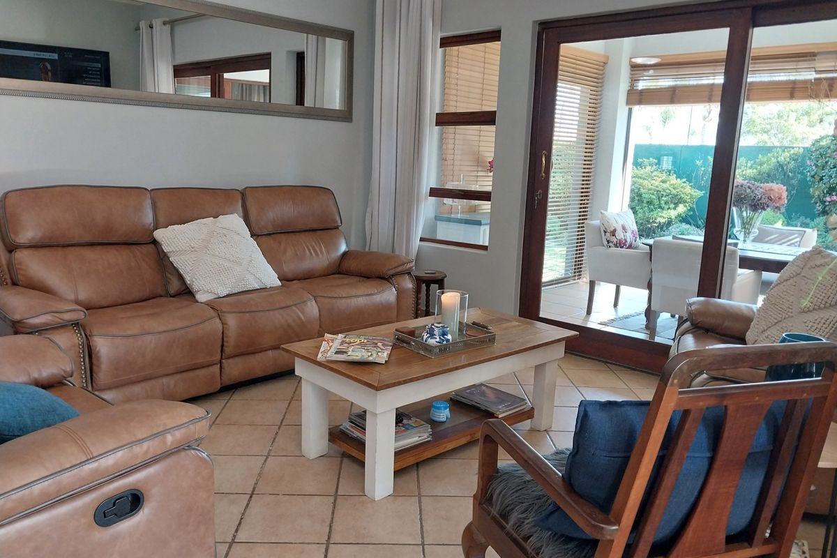 A comfortable living room featuring tiled flooring and large sliding glass doors that provide natural light and access to the outdoor patio area.