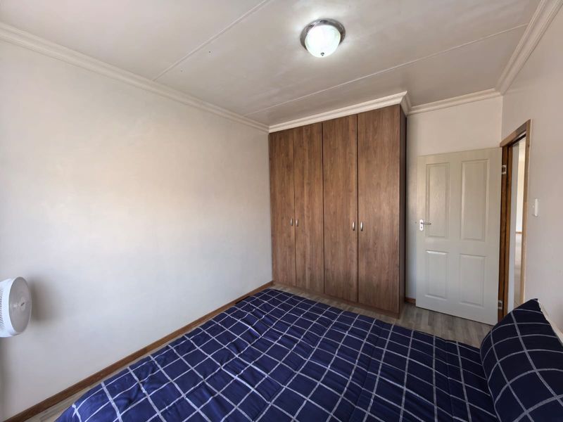 A bedroom featuring built-in wooden cupboards, coved ceiling detailing, and a neutral interior finish.
