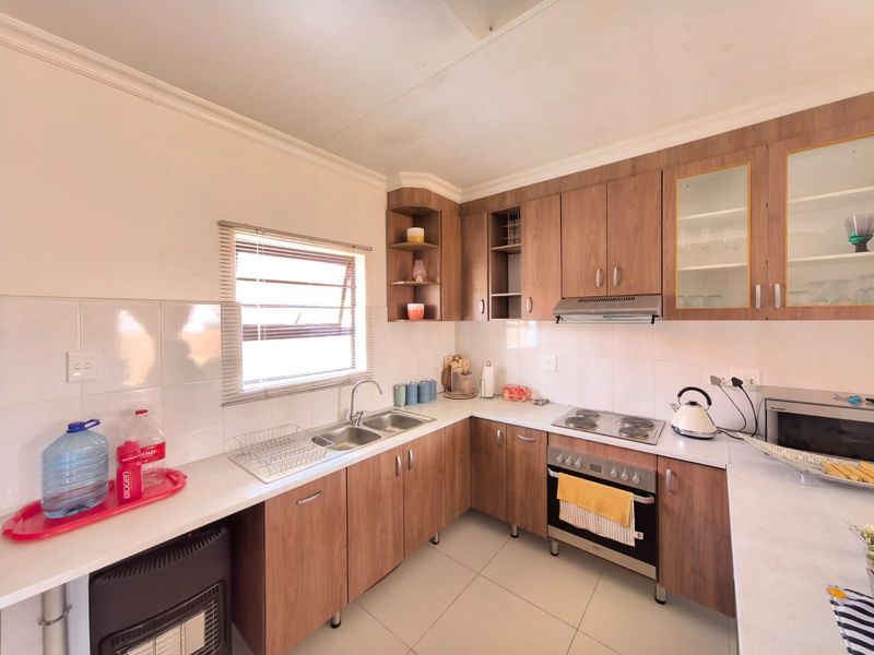 A functional kitchen featuring wood-look cabinetry, laminate countertops, a built-in oven with electric hob, and a tiled backsplash.