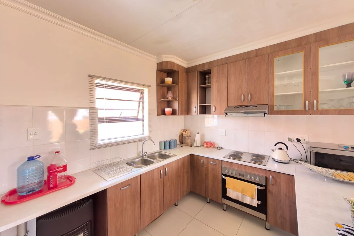 A functional kitchen featuring wood-look cabinetry, laminate countertops, a built-in oven with electric hob, and a tiled backsplash.