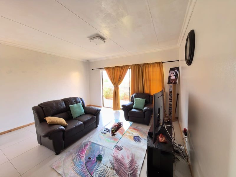 A bright living room featuring tiled flooring, coved ceilings, and a sliding glass door providing access to the outdoor area.