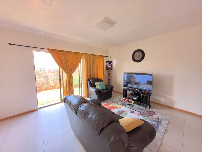 A living room featuring tiled flooring and a sliding glass door providing access to the exterior.