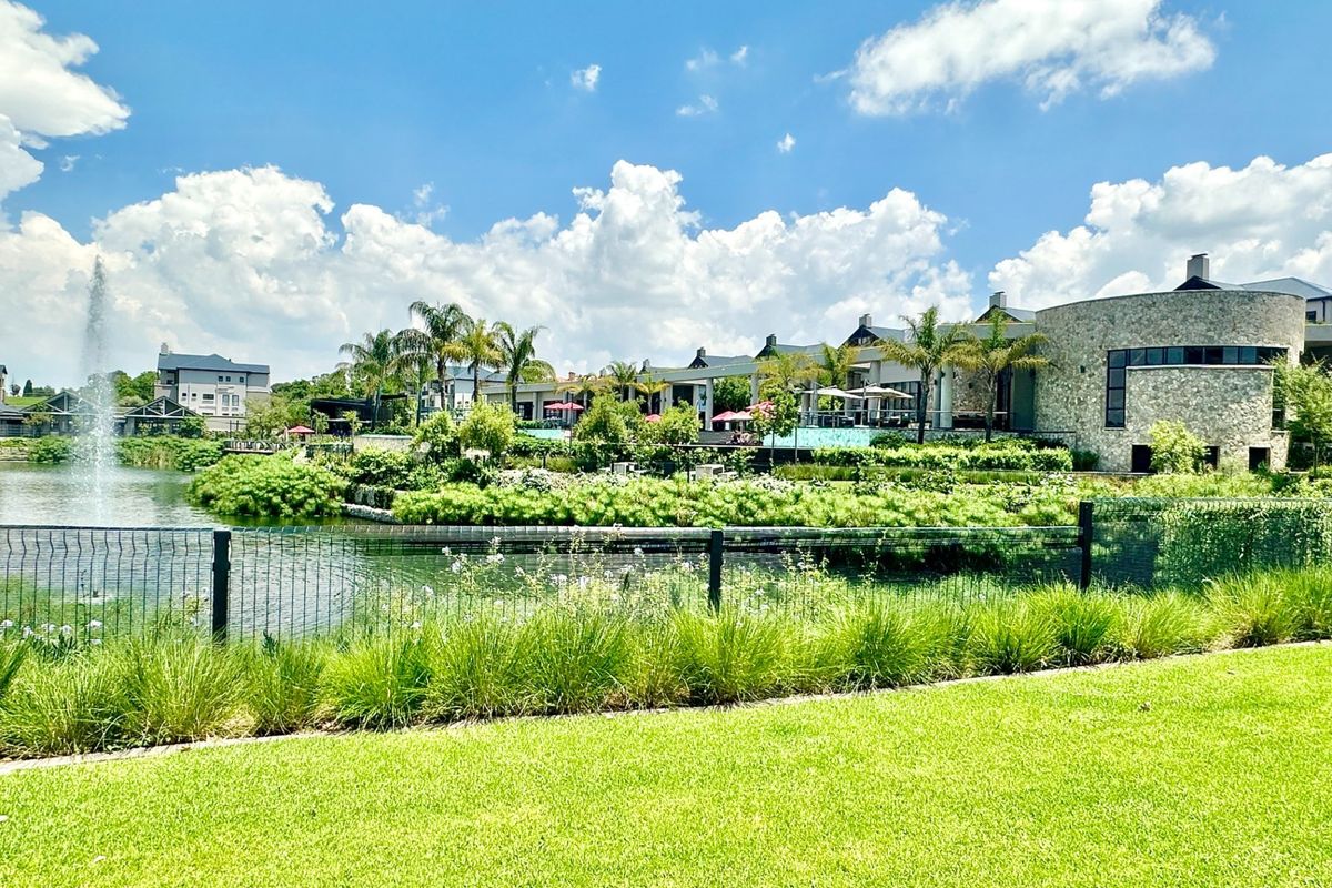 A scenic view of the property's rear exterior, featuring a landscaped garden, a water feature, and stone-clad architectural elements.