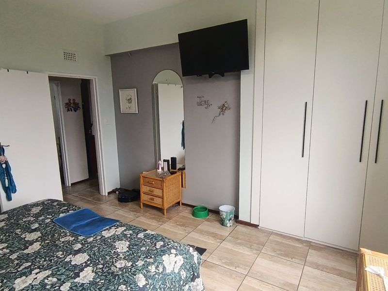 A bedroom featuring tiled flooring and a large built-in wardrobe with modern handles, providing ample storage space.