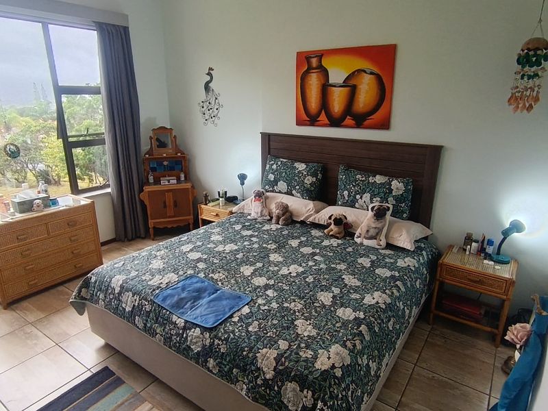 A spacious bedroom featuring large windows that provide natural light and views, complemented by durable tiled flooring throughout the room.