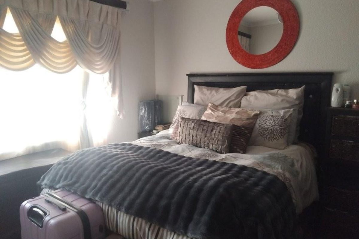 A cozy bedroom featuring a built-in window seat and decorative window pelmet, offering a comfortable and functional sleeping space.