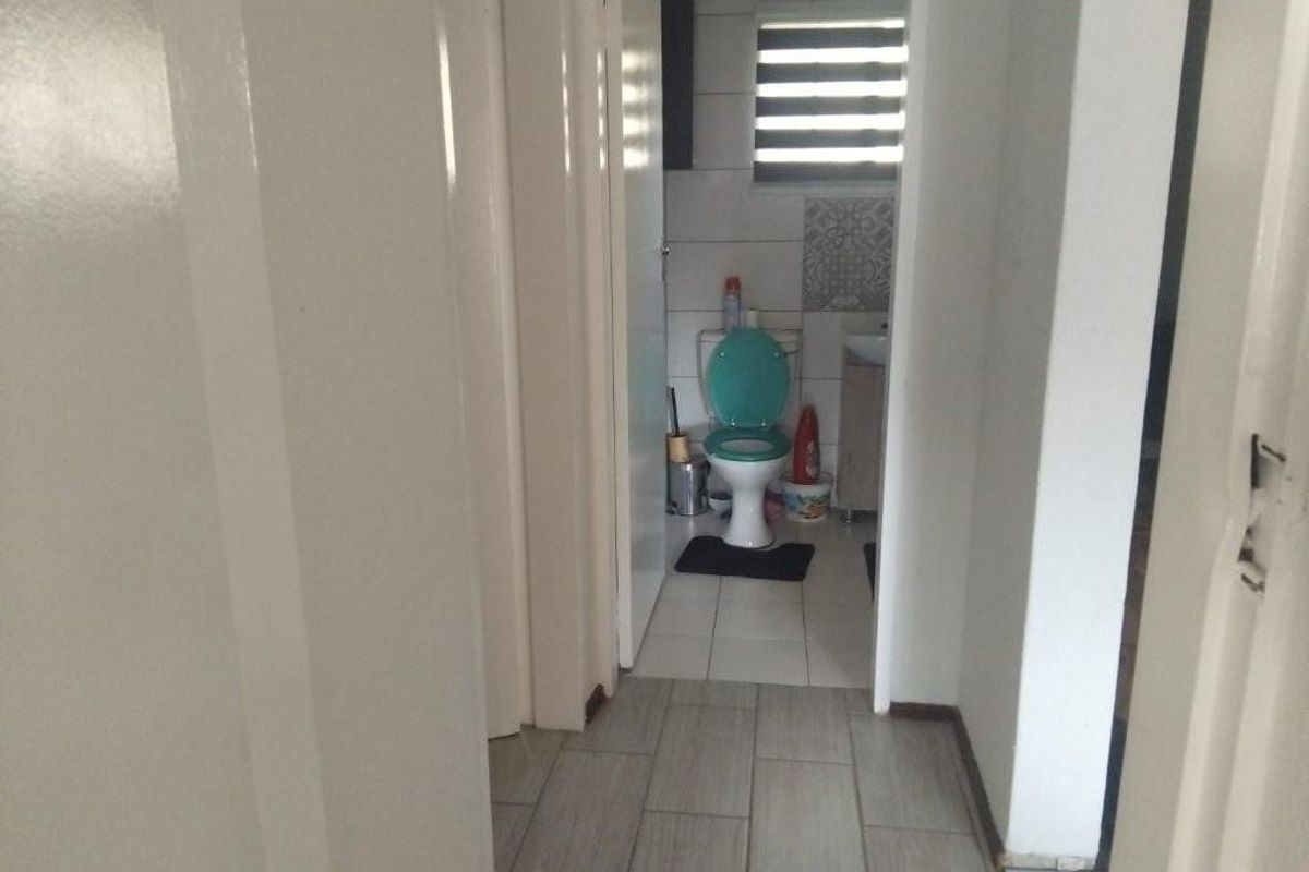 A functional bathroom featuring tiled flooring and walls, equipped with a standard toilet and vanity unit.