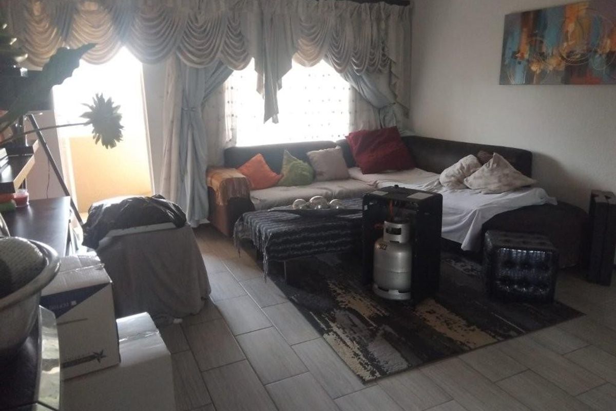 A living room area featuring tiled flooring and access to an outdoor balcony through a sliding door.
