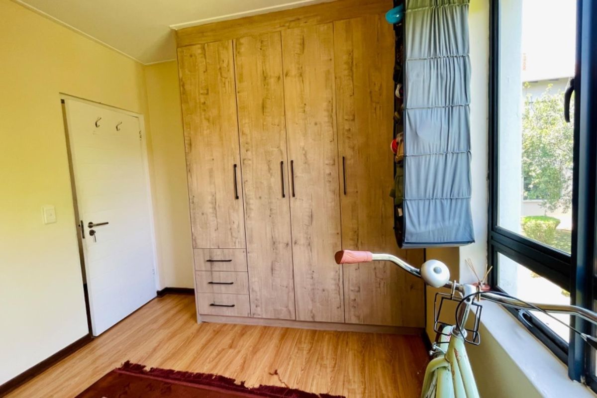 A bedroom featuring wood-look laminate flooring and a large built-in wardrobe with modern handles, providing ample storage space.