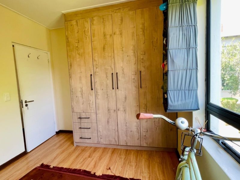 A bedroom featuring wood-look laminate flooring and a large built-in wardrobe with modern handles, providing ample storage space.
