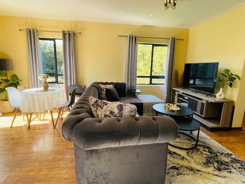 Open-plan living and dining area featuring laminate flooring and large windows that provide ample natural light.