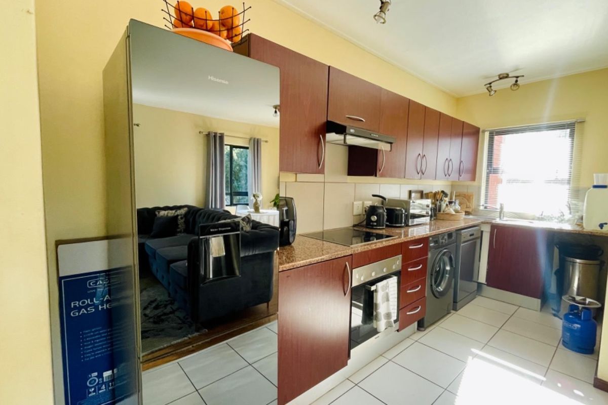 A functional kitchen featuring dark wood cabinetry, granite countertops, integrated appliances, and tiled flooring, offering a practical layout for daily cooking and preparation.